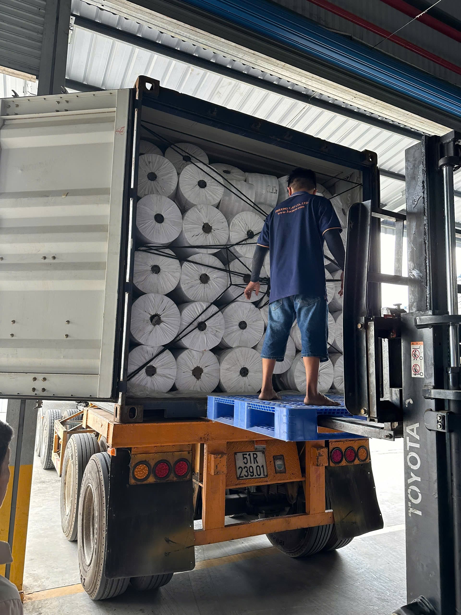 A Phuong Cat employee inspecting material rolls loaded inside a container