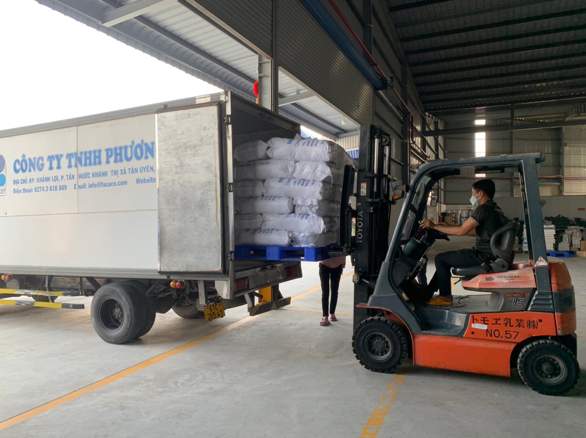 Forklift loading bags of raw materials onto a Phuong Cat truck