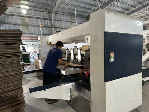 Staff operating the automatic carton gluing machine at the Phuong Cat factory